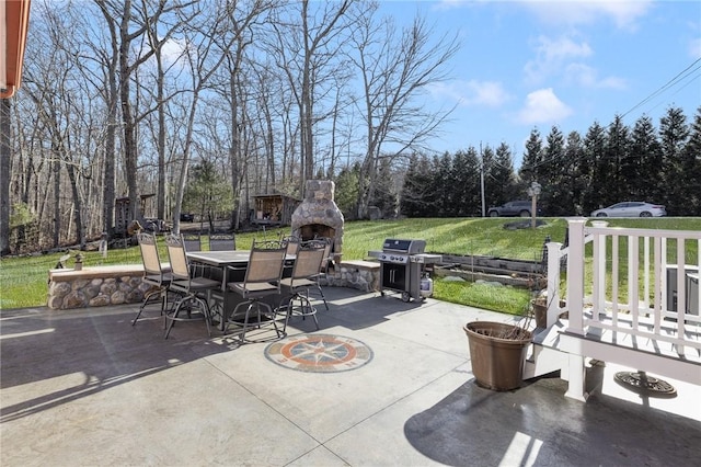 view of patio featuring a grill, an outdoor stone fireplace, and outdoor dining area