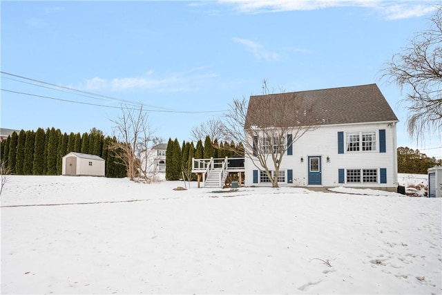 snow covered rear of property with a storage unit