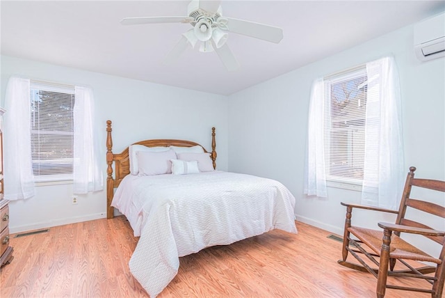 bedroom with ceiling fan, light hardwood / wood-style floors, and an AC wall unit