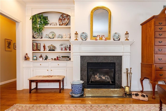 sitting room with hardwood / wood-style floors and built in shelves