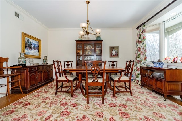 dining area with a notable chandelier, light hardwood / wood-style flooring, and crown molding