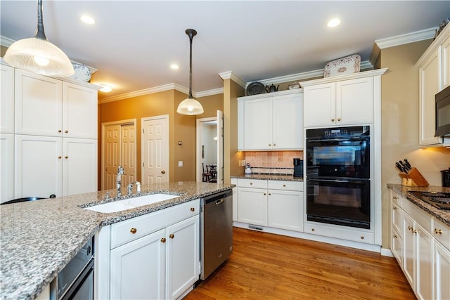 kitchen featuring light hardwood / wood-style flooring, hanging light fixtures, light stone countertops, black appliances, and sink