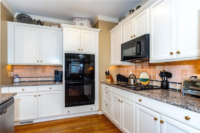 kitchen featuring dark stone counters, ornamental molding, black appliances, and white cabinets