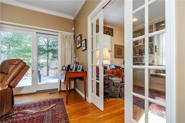 doorway to outside featuring light wood-type flooring, french doors, and ornamental molding