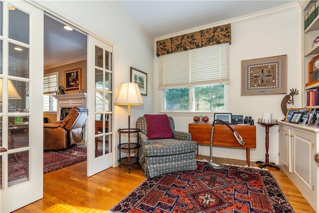 sitting room with french doors, crown molding, and light hardwood / wood-style floors