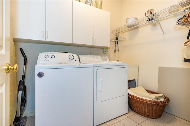 laundry area with washing machine and dryer, cabinets, and light tile patterned floors