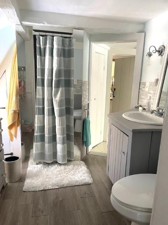 bathroom with toilet, hardwood / wood-style flooring, vanity, and tasteful backsplash