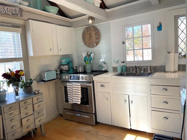 kitchen featuring white cabinetry, stainless steel range with electric cooktop, light hardwood / wood-style floors, sink, and backsplash