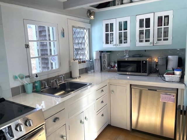 kitchen featuring sink, stainless steel appliances, white cabinetry, and backsplash