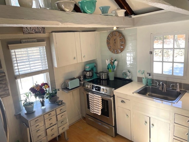 kitchen with sink, light wood-type flooring, white cabinets, stainless steel range with electric cooktop, and tasteful backsplash