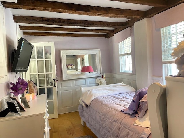 bedroom featuring light hardwood / wood-style floors and beam ceiling