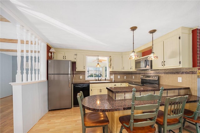 kitchen with a breakfast bar area, stainless steel appliances, backsplash, sink, and kitchen peninsula