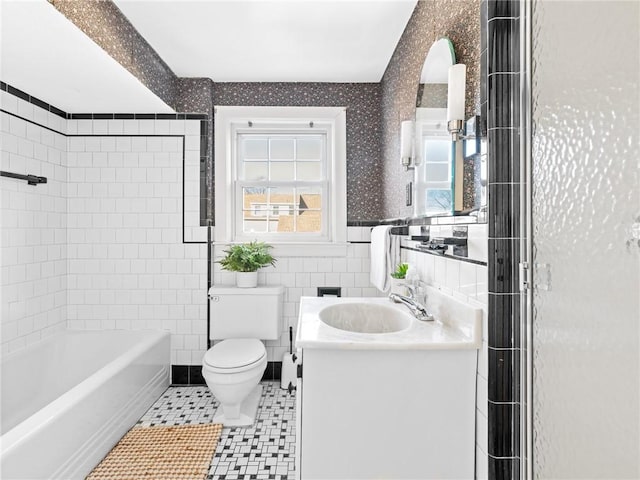 full bathroom with tile walls, vanity, tiled shower / bath, toilet, and tile patterned floors