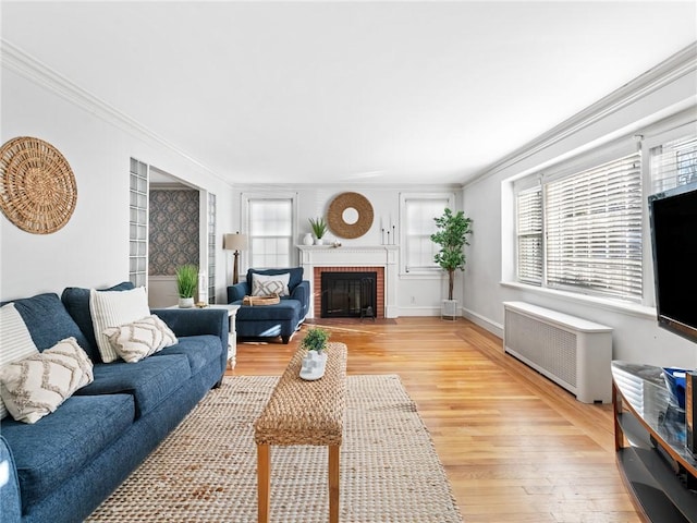 living room with light hardwood / wood-style flooring, radiator heating unit, ornamental molding, a brick fireplace, and built in features