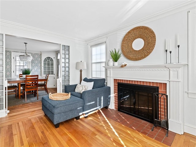 living room featuring ornamental molding, hardwood / wood-style flooring, and a brick fireplace