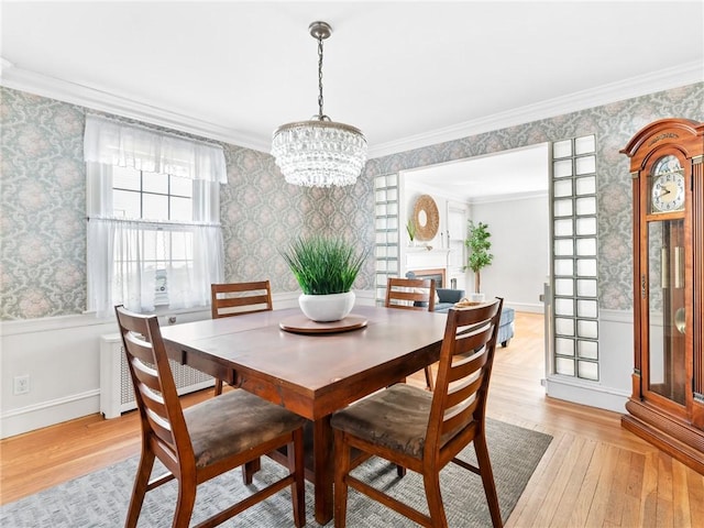 dining area with radiator heating unit, light wood-type flooring, an inviting chandelier, and ornamental molding