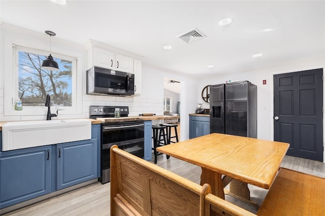 kitchen featuring blue cabinetry, stainless steel appliances, light wood-type flooring, decorative backsplash, and sink