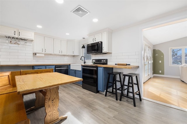 kitchen with wooden counters, range with electric cooktop, a breakfast bar area, blue cabinets, and white cabinetry