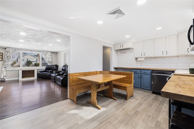 kitchen with light hardwood / wood-style flooring, butcher block counters, black appliances, blue cabinets, and white cabinetry