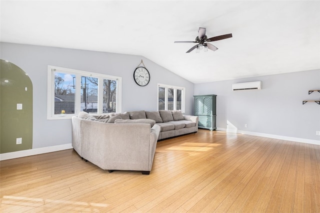 living room featuring a wall mounted air conditioner, light hardwood / wood-style flooring, ceiling fan, and lofted ceiling