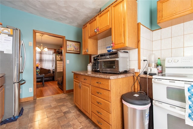 kitchen featuring backsplash, double oven range, stainless steel refrigerator, and an inviting chandelier