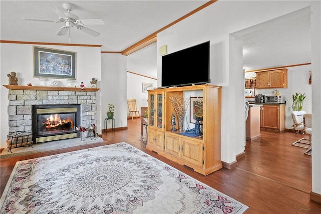 living room with a fireplace, ornamental molding, dark hardwood / wood-style floors, and ceiling fan