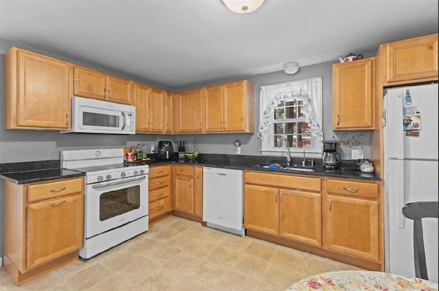 kitchen with sink, white appliances, and dark stone countertops