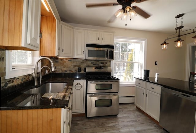 kitchen featuring sink, stainless steel appliances, white cabinetry, and a baseboard heating unit