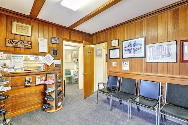 carpeted office space featuring beam ceiling, crown molding, and wood walls