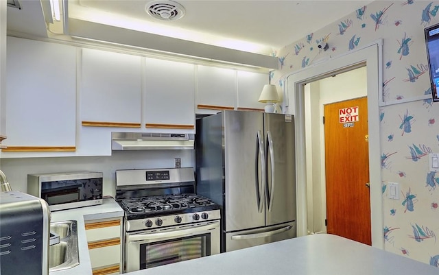 kitchen with exhaust hood, appliances with stainless steel finishes, and white cabinetry