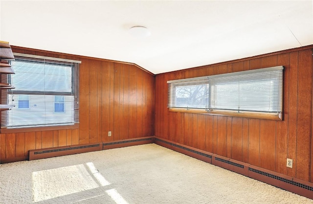 carpeted spare room featuring vaulted ceiling and wood walls