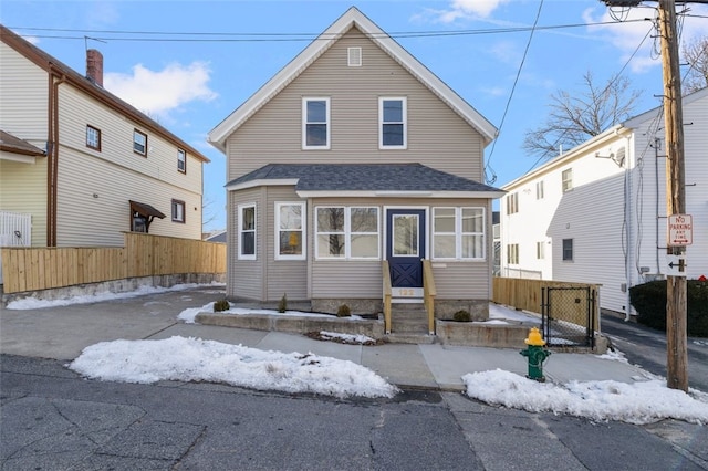 view of front of property with fence, driveway, and roof with shingles