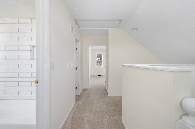 corridor with vaulted ceiling and light colored carpet