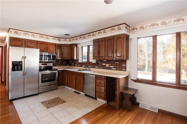 kitchen featuring light hardwood / wood-style floors, appliances with stainless steel finishes, sink, and decorative backsplash