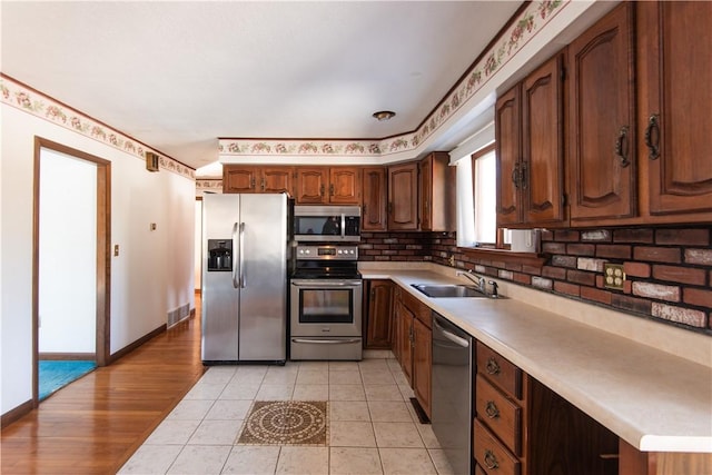 kitchen with appliances with stainless steel finishes, light tile patterned flooring, sink, and tasteful backsplash