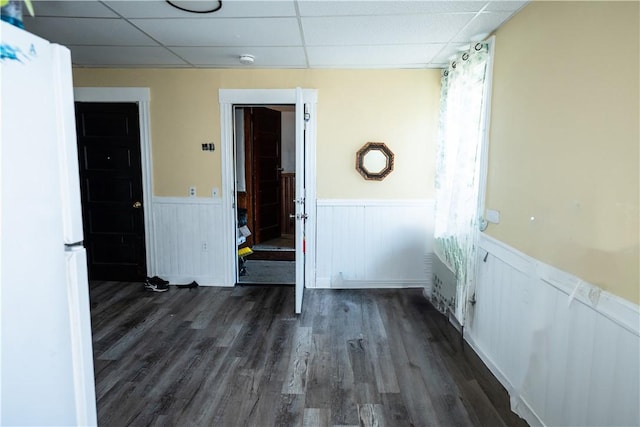 empty room with dark hardwood / wood-style floors and a drop ceiling