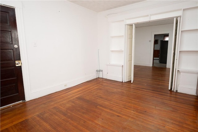 unfurnished room featuring built in features and dark hardwood / wood-style floors