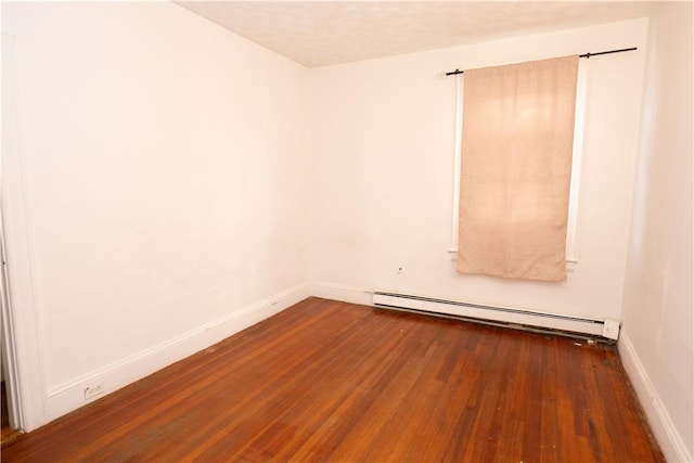 unfurnished room with dark wood-type flooring and a baseboard heating unit