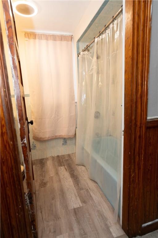 bathroom featuring wood-type flooring and shower / bath combo with shower curtain