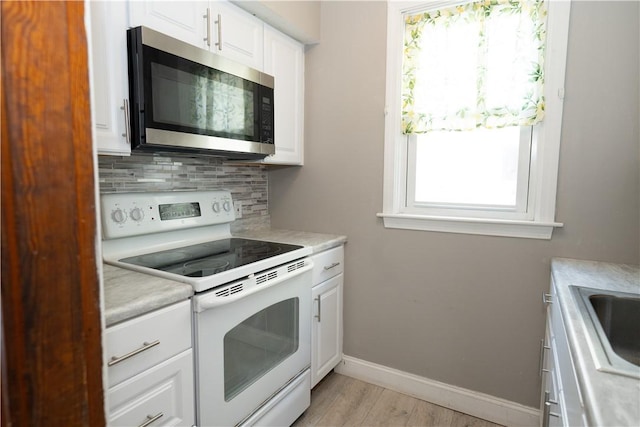 kitchen with light hardwood / wood-style flooring, sink, backsplash, white range with electric stovetop, and white cabinets