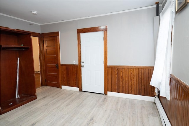 unfurnished bedroom featuring light hardwood / wood-style floors, wooden walls, ornamental molding, and a baseboard radiator