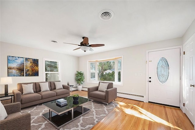 living room with ceiling fan, wood-type flooring, and a baseboard heating unit