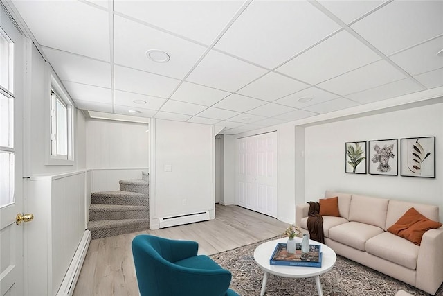 living room featuring a paneled ceiling, light hardwood / wood-style floors, and a baseboard heating unit