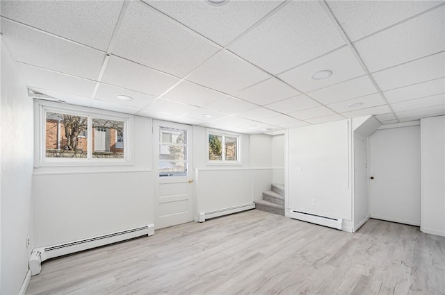 basement featuring baseboard heating, a drop ceiling, and light hardwood / wood-style floors