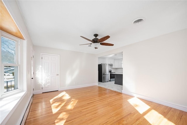 unfurnished living room featuring a baseboard radiator, light wood-type flooring, and ceiling fan