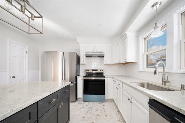 kitchen with white cabinetry, stainless steel appliances, decorative light fixtures, light stone countertops, and sink