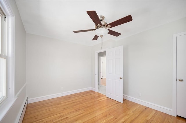 spare room featuring baseboard heating, ceiling fan, and light wood-type flooring