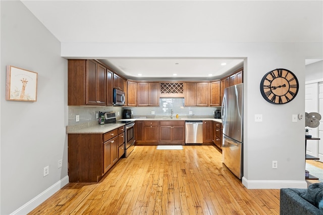 kitchen with sink, decorative backsplash, light wood-type flooring, and stainless steel appliances