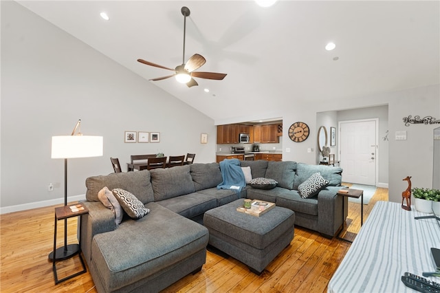 living room with light hardwood / wood-style flooring, ceiling fan, and vaulted ceiling