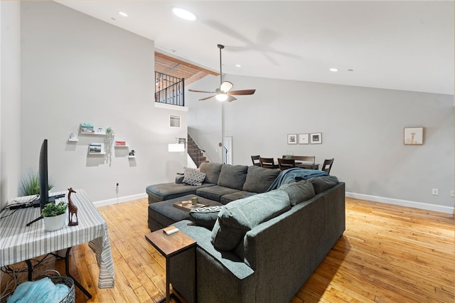 living room featuring light hardwood / wood-style floors, high vaulted ceiling, and ceiling fan